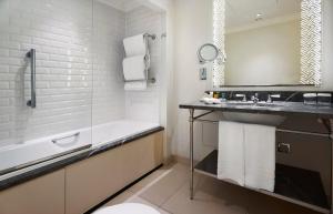 a bathroom with a tub and a sink and a shower at The Waldorf Hilton in London +37 photos