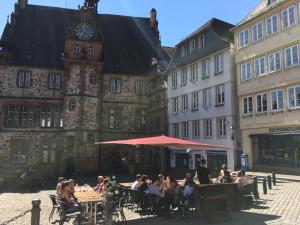 people sitting at tables in front of a building with a clock tower at Ferienwohnung - Marburg in Marbach