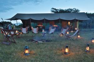 una tenda con sedie, tavolo e luci nell'erba di Pakulala Safari Camp - Ngorongoro a Ngorongoro