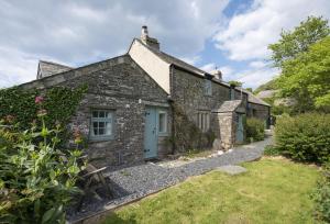 an old stone cottage with a blue door at Besloe in Delabole