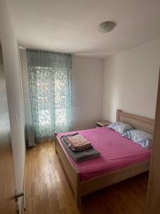 a bedroom with a bed with pink sheets and a window at District Loft in Podgorica