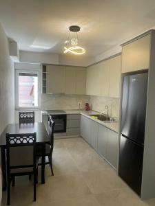 a kitchen with a table and a black refrigerator at S&S City Apartment in Shkodër