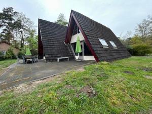 a house with a patio with a table and two green umbrellas at Duo family bungalow Vosvilla Limburg in Stramproy