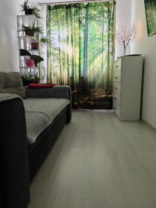 un soggiorno con divano e una finestra con alberi di HANA Apartament a Târgu-Mureş