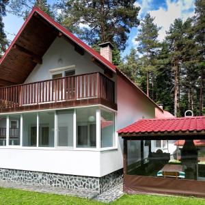 une maison avec un toit rouge et un balcon dans l'établissement Вилно селище Тракия- почивка сред природата, à Tsigov Chark