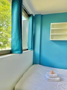 ein Bett in einem Zimmer mit einer blauen Wand und einem Fenster in der Unterkunft Studio 65 Rénové et Équipé - Nancy Brabois proche CHRU,CESI,FAC in Vandoeuvre-lès-Nancy