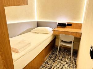 a small room with a bed and a desk and a chair at AQ miniHOTEL in Shymkent
