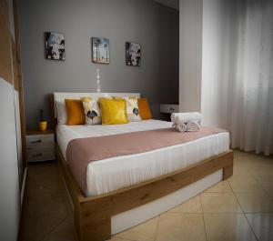 a bedroom with a large bed with yellow pillows at Endy Apartaments in Orikum
