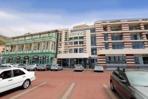 a parking lot with cars parked in front of a building at Surfers Empire Penthouse in Muizenberg