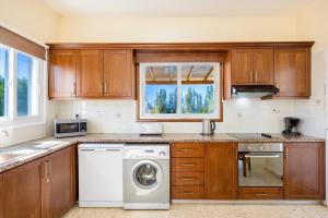 a kitchen with a washing machine and a window at Villa Christina in Argaka