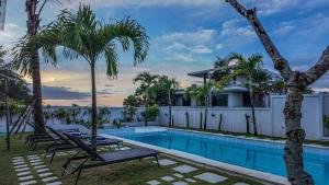 a villa with a swimming pool and palm trees at Gandum Villa Complex - Luxury Boutique Stay Uluwatu in Uluwatu