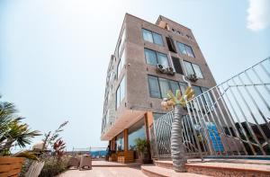Plus 33 Hotel في Sakumona: مبنى أمامه شجرة نخيل