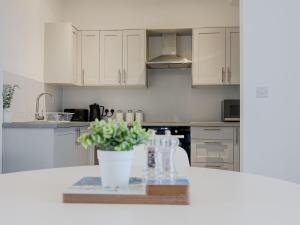 a kitchen with white cabinets and a table with a potted plant at Nelson Road North in Great Yarmouth
