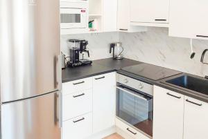 a kitchen with white cabinets and a black counter top at Lomahuoneisto Himoksen Alppirinne in Jämsä