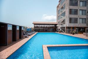 Plus 33 Hotel في Sakumona: مسبح أزرق كبير بجوار مبنى