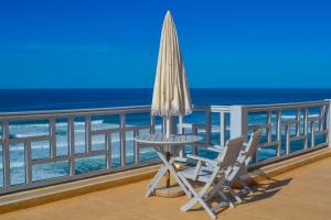 an umbrella and a table and chairs on a balcony with the ocean at Villaseahouse in Sidi Ifni