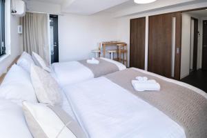 two beds in a room with white sheets and towels at The Peak Tsutenkaku Elite in Osaka +60 photos