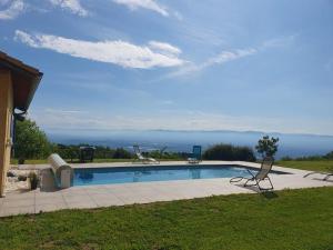 a swimming pool with two chairs in the grass at Évasion en Ardèche villa de Charme avec Piscine in Saint-Romain-de-Lerps