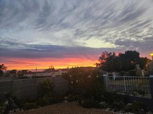 Una puesta de sol sobre un patio trasero con una valla delante de una valla. en Duifie, en Ciudad del Cabo
