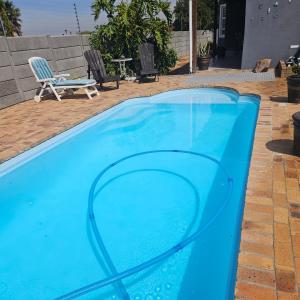 una piscina azul con una silla y una mesa en Duifie, en Ciudad del Cabo