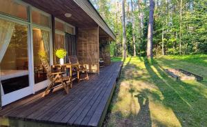 a wooden porch of a cabin with a table and chairs at Viesuliškės Lakeside Glamping in Lakaja