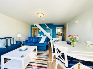 a living room with a blue couch and a table at Ynyslas View in Aberdyfi