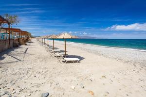 a row of umbrellas and chairs on a beach at Sage Villa by Vintage Travel in Tavronitis