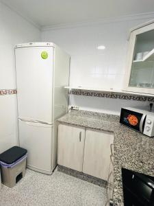 a kitchen with a white refrigerator and a microwave at Apartamento Playa Torreón in Benicàssim
