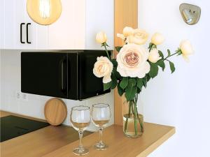 eine Vase mit Rosen und zwei Gläser Wein in der Unterkunft Live Punta Columbus Pool & Beach Front in Punta del Hidalgo