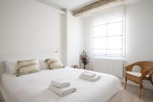 a white bedroom with a large white bed with towels on it at Apartamento Vargas 2BDR in Santander
