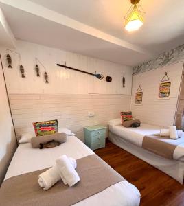 two beds in a room with white walls and wooden floors at LA MAR SALADA in Lastres