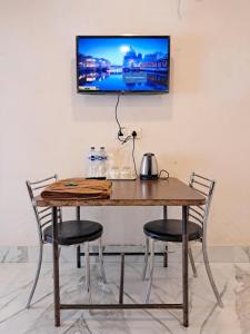 a wooden table with chairs and a television on a wall at LD Guest House, Ayodhya in Ayodhya