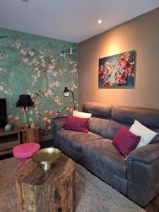 a living room with a brown couch and a painting at Boshuisje Het Bosnest - de Specht bungalow met privétuin op Hoefbos Otterlo Veluwe in Otterlo
