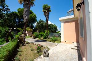 dos palmeras en un patio junto a una casa en Casa Lamacchia by CorfuEscapes, en Corfú