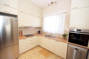 Una cocina con gabinetes blancos y un refrigerador de acero inoxidable. en Casa Lamacchia by CorfuEscapes, en Corfú 24 fotos más