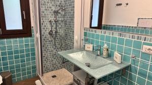 een blauwe betegelde badkamer met een wastafel en een douche bij La casa delle Stelle by Ca-Sa Check in San Teodoro