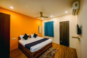 a bedroom with a bed with orange walls and a television at Hotel Laughing Buddha in Bhubaneshwar