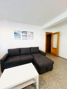a living room with a black couch and a table at Apartamento Playa Torreón in Benicàssim