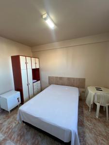 a bedroom with a large white bed and a table at Hotel Gerais Business in Montes Claros