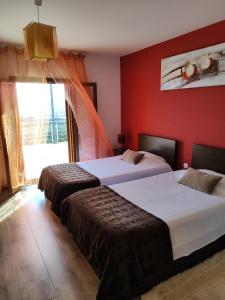 two beds in a room with a red wall at Casa das Argolas in Macedo de Cavaleiros +69 photos
