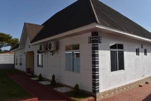 a small white house with a black roof at Volunteer House in Msaranga
