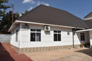 a white house with a black roof at Volunteer House in Msaranga +10 photos
