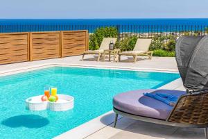 una piscina con una silla y una mesa con bebidas en Kamelia Villa 2, en Hersonissos