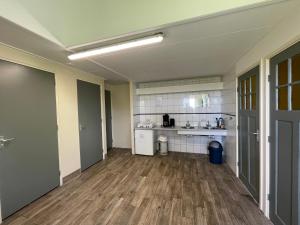 an empty room with a kitchen with wooden floors at Duintentje in Schiermonnikoog