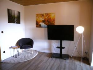 un soggiorno con TV e sedia di Ferienwohnung am Hotel "Mein Bergblick" a Goslar