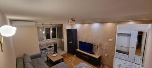a living room with a couch and a television at Anzoli Apartmani Centar Niksić in Nikšić
