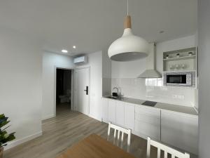 a kitchen with white cabinets and a microwave at Island Home Fuerteventura in Corralejo