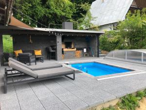a backyard with a swimming pool and a patio with a barbecue at Chata Čaks in Nižný Klátov