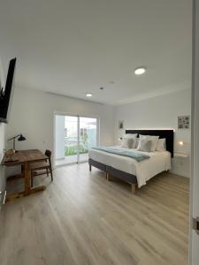 a white bedroom with a bed and a table at Island Home Fuerteventura in Corralejo