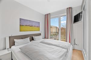 ein weißes Schlafzimmer mit einem großen Bett und einem Fenster in der Unterkunft DünenResort Binz DünenResort Binz 135 in Binz